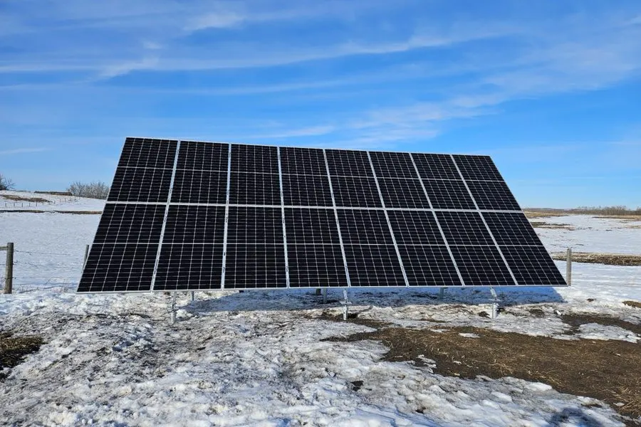 Ground-mount solar array producing on Alberta acreage during winter with crop stubble visible