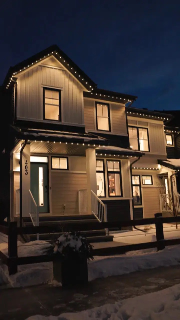 Alberta home in winter snow with warm white permanent roofline lighting glowing at dusk